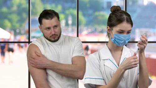 Nurse Preparing Injection for Man in Clinic