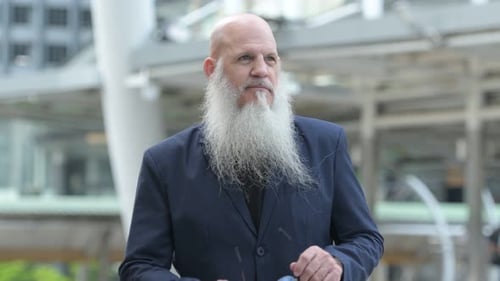 Mature Bearded Bald Businessman Wearing Eyeglasses in the City Outdoors