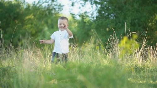 Young Boy Running Through Grassy Field on Sunny Day