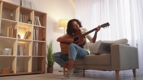 Young Woman Plays Guitar in Living Room