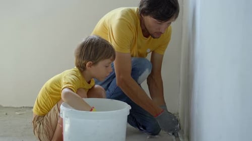 Father and Son Plastering White Wall Together