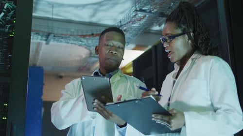 Afroamerikanische Computertechniker verwenden ein Tablet, das im Geschäftsserverraum arbeitet