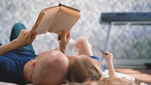 Father and Daughter Reading Book Together at Home