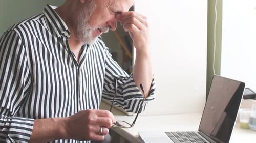 Tired Senior Man Rubbing Eye While Working