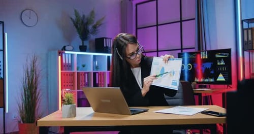 Morena con auriculares sentada frente a la computadora durante una videoconferencia con colegas