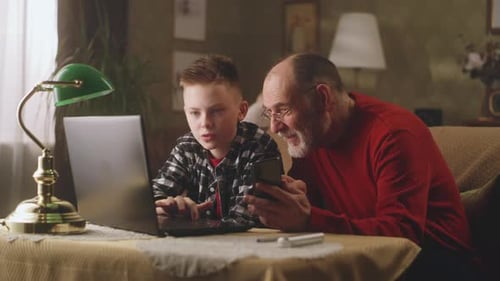 Child and Senior Using Technology Together Indoors
