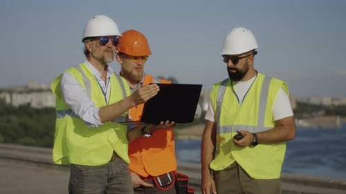 Builders Using Laptop on Construction Site