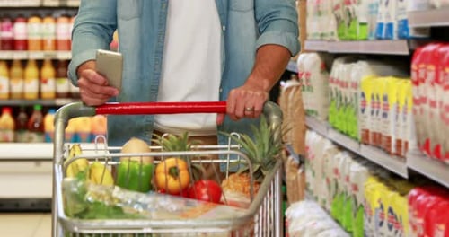 Senior man texting in the supermarket