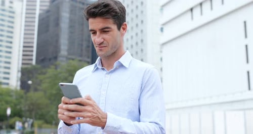Smiling Man Using Smartphone in City