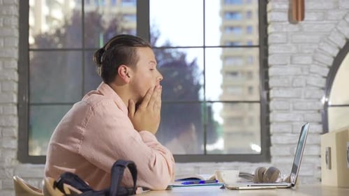 Thoughtful Man Working at Desk on Laptop