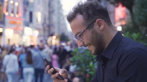 Laughing young man texting on the phone.