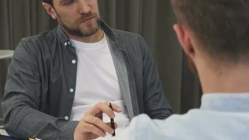 Abgeschnittene Aufnahme eines reifen Geschäftsmannes, der seinem Kollegen bei dem Treffen aufmerksam zuhört