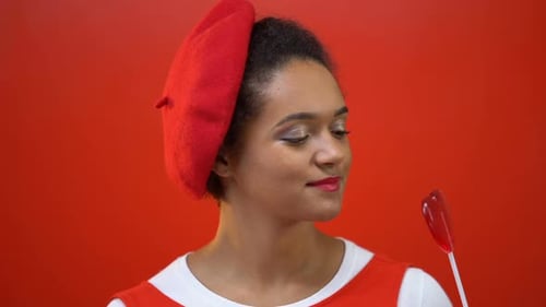 Woman with Red Beret Holding Heart Lollipop