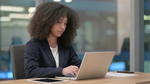 Young Woman Typing on Laptop at Office Desk