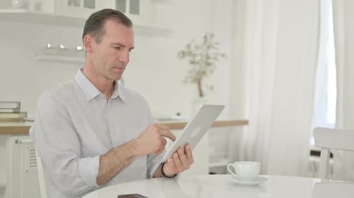 Man Using Tablet Device at Home Table