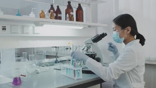 Scientist Researching Under Microscope in Modern Laboratory