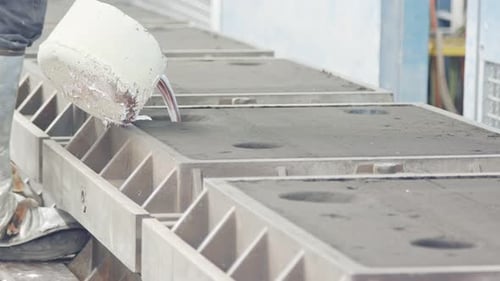 Workers in a foundry pouring liquid Aluminum to a sand cast