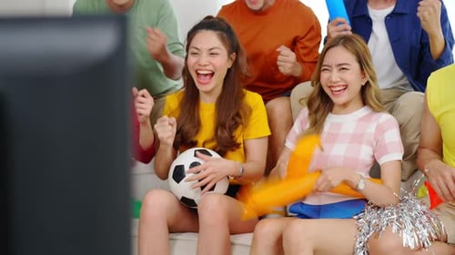4K Group of Asian man and woman friends watching sports soccer on television together at home.