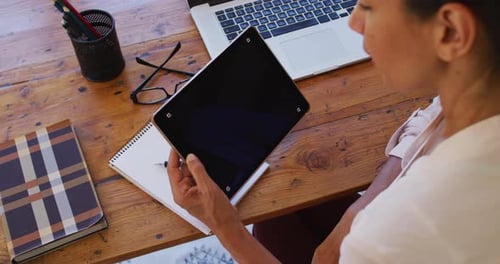 Woman Holding Tablet with Pen at Wooden Desk