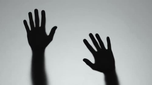 Shadow of Hands Making Gestures Against Gray Background