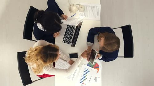 Group of Female Marketers Works in the Office with Documents and Diagrams