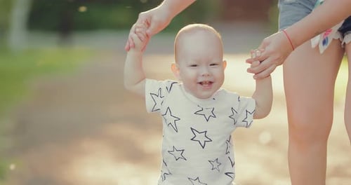 Happy Baby Learning to Walk With Caregiver Outdoors
