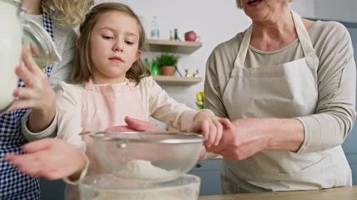 Handvideo von Mädchen mit Mutter und Großmutter beim Sieben von Mehl. Aufgenommen mit einer ROTEN Helium-Kamera in 8K.