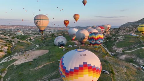 Hot air balloons fly over the mountainous landscape of Cappadocia, Turkey.
