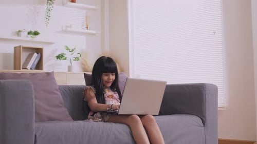 Girl Typing on Laptop Computer on Living Room Couch