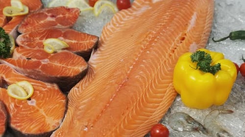 Composition of Trout and Salmon Steaks Lies on Ice in Showcase of Supermarket