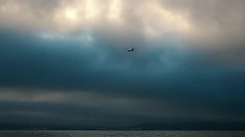 Airplane Flying Over the Water on a Cloudy Day