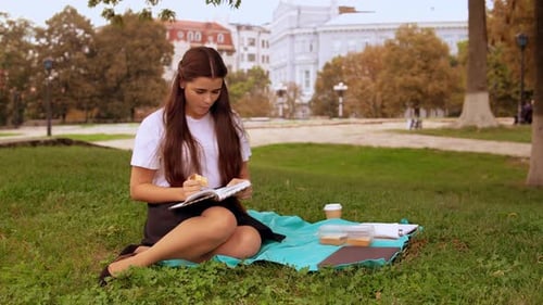Woman Reading Book and Eating in the Park