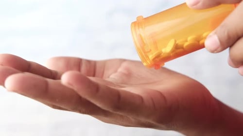 Männerhand mit verschütteten Medikamenten aus dem Pillenbehälter