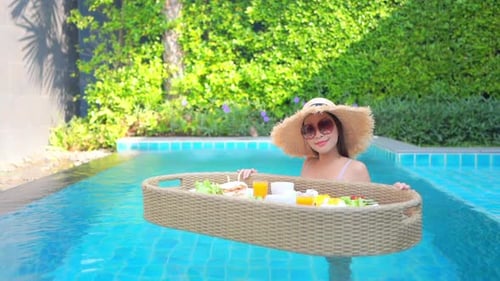 Woman with floating breakfast in pool
