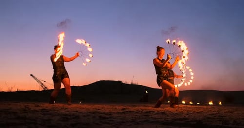Professionelle Künstler zeigen eine Feuershow bei einem Sommerfestival im Sand in Zeitlupe