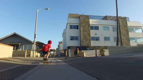 A boy rides a skateboard in a neighborhood alley street.