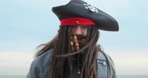 Sloppy Pirate with Cocked Hat Waves Hands on Sea Beach