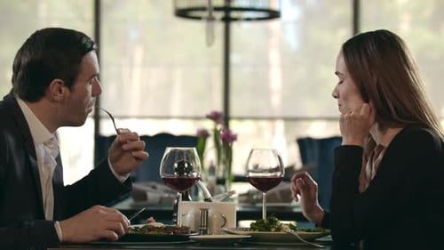 Business Couple Eating Dinner at Restaurant. Man and Woman Drinking Wine in Cafe