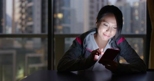 Woman Using Mobile Phone at Night with City View