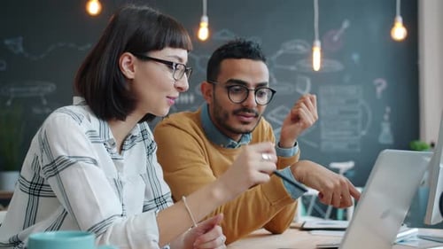 Girl and Guy Mixed Race Business Team Talking Using Laptop in Shared Office