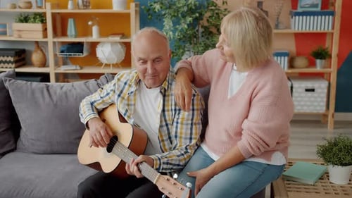 Senior Couple Playing Guitar at Home Together