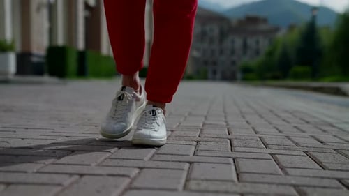 Sportlich gekleidete Frau spaziert am Sommermorgen in der Innenstadt Nahaufnahme von Füßen in sportlichen Turnschuhen