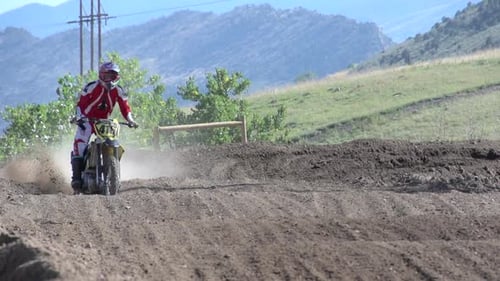 A young man riding a motocross dirt motorcycle.