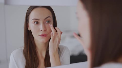 Woman Applying Eye Cream and Smiling