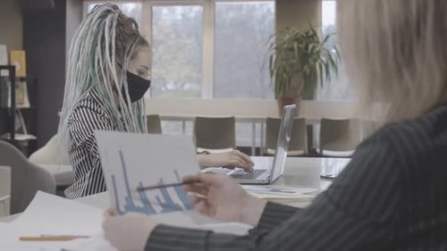 Portrait d'une femme millénaire concentrée et confiante avec des dreadlocks dans un masque facial Covid au travail
