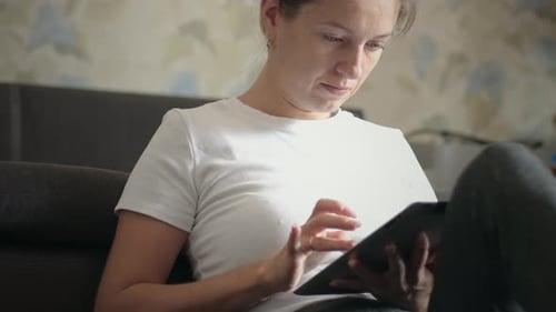 Woman Using Tablet on Gray Couch at Home