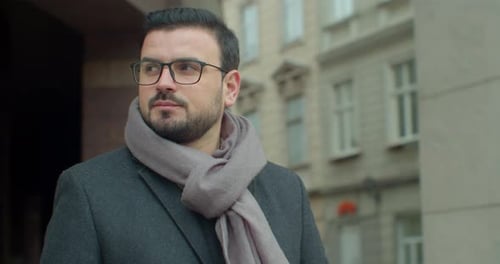 Portrait of a Handsome Businessman in Glasses Standing on a Modern Office Building Background. Close