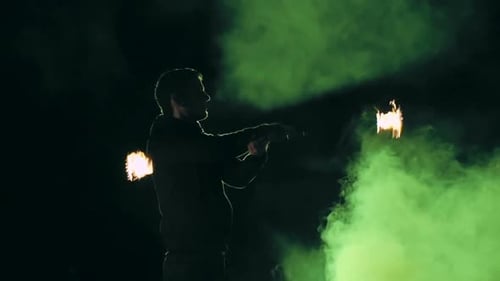 Man Juggling Flaming Torches at Night with Smoke