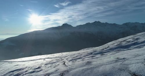 Luftaufnahme von oben über den verschneiten Winterberg mit Skipisten bei sonnigem Tag mit Wolken