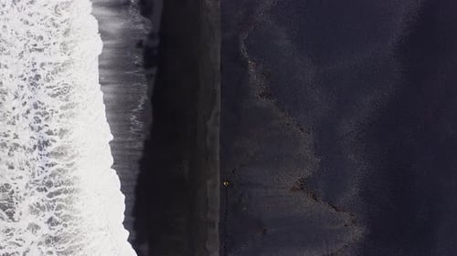 Drone Over Black Sand Beach With Mountain Range In Background